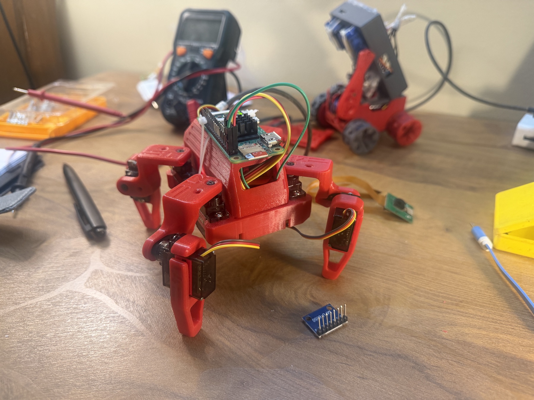 Molty's red articulated legs, servos, wiring, and Raspberry Pi visible on a workbench